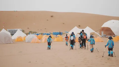 营员走向沙漠里的帐篷营地