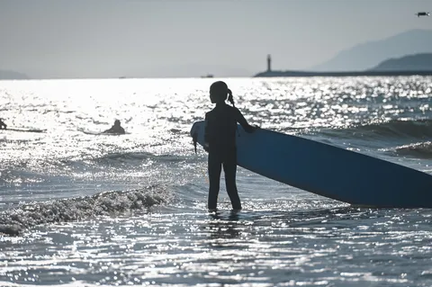 海南营员抱着冲浪板站在海边