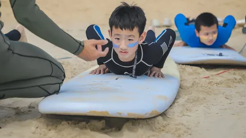海南营教练在沙滩上指导营员练习冲浪起乘动作