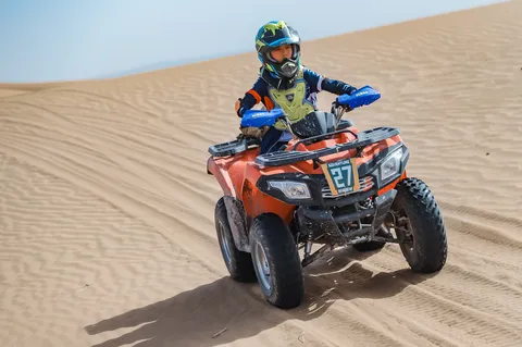 沙漠 ATV 营员戴着头盔，双手握车把驾驶四轮车