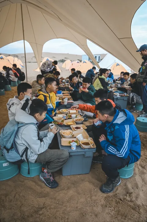 营员在帐篷下与伙伴一起用餐