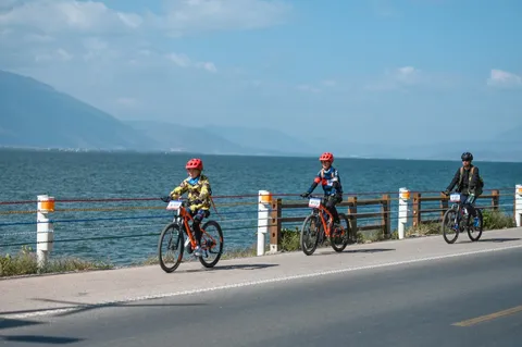 三名营员沿湖边公路骑行